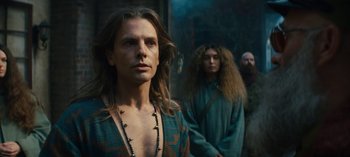 Movie still from “Sweet Tooth” (2021), created by Jim Mickle – A man with long brown hair standing next to a woman with long brown hair; Medium shot, Over the shoulder angle