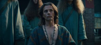 Movie still from “Sweet Tooth” (2021), created by Jim Mickle – A man with long blonde hair wearing a blue robe; Medium shot, Low angle