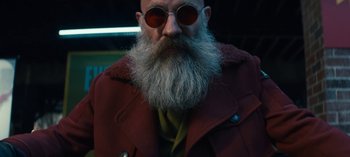 Movie still from “Sweet Tooth” (2021), created by Jim Mickle – A man with a long beard wearing sunglasses and a red jacket; Close Up shot, Low angle