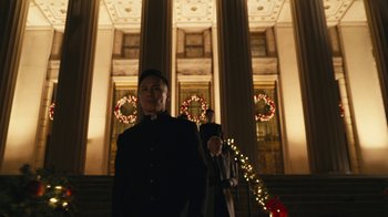 Movie still from “Mr. Robot” (2015), created by Sam Esmail – A man in a black suit standing in front of a building; Medium shot, Low angle