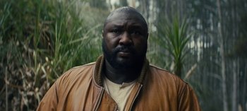 Movie still from “Sweet Tooth” (2021), created by Jim Mickle – A man in a brown jacket standing next to some trees; Close Up shot, Low angle