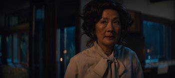 Movie still from “Sweet Tooth” (2021), created by Jim Mickle – An older woman wearing a white shirt and a white bow tie; Close Up shot, Over the shoulder angle