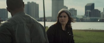 Movie still from “Synchronic” (2019), directed by Justin Benson – A woman in a black jacket and a gray hat is standing in front of another woman; Close Up shot, Over the shoulder angle