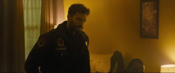 Movie still from “Synchronic” (2019), directed by Justin Benson – A man with a beard is standing in a dark room; Close Up shot, Over the shoulder angle