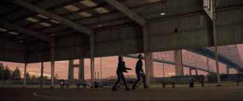 Movie still from “Synchronic” (2019), directed by Justin Benson – Two people are walking in an open area near a bench; Extreme Wide shot, Low angle