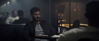 Movie still from “Synchronic” (2019), directed by Justin Benson – A man sitting at a table with a bottle of beer; Medium shot, Over the shoulder angle