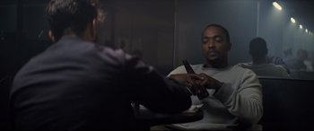 Movie still from “Synchronic” (2019), directed by Justin Benson – A man sitting at a table holding a cell phone; Medium shot, Over the shoulder angle