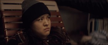 Movie still from “Synchronic” (2019), directed by Justin Benson – A person sitting on a bench looking at the camera; Close Up shot, Over the shoulder angle