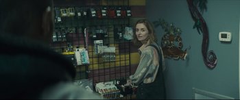 Movie still from “Synchronic” (2019), directed by Justin Benson – A woman standing next to a wall in a store; Medium shot, Over the shoulder angle