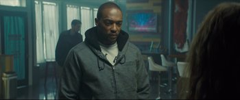 Movie still from “Synchronic” (2019), directed by Justin Benson – A man standing in front of a tv in a room; Medium shot, Low angle