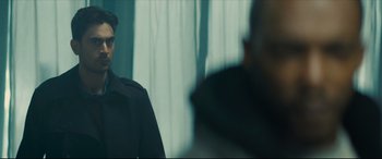 Movie still from “Synchronic” (2019), directed by Justin Benson – A man standing in front of a window with curtains; Close Up shot, Over the shoulder angle