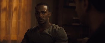Movie still from “Synchronic” (2019), directed by Justin Benson – A man in a brown t - shirt is looking at the camera; Close Up shot, Over the shoulder angle
