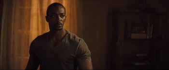 Movie still from “Synchronic” (2019), directed by Justin Benson – A man standing in a dark room with a light on; Close Up shot, Over the shoulder angle