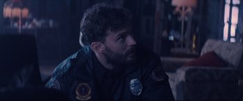 Movie still from “Synchronic” (2019), directed by Justin Benson – A man with a beard is sitting in a dark room; Close Up shot, Over the shoulder angle