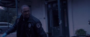 Movie still from “Synchronic” (2019), directed by Justin Benson – A police officer is standing in a dark room; Medium shot, Low angle