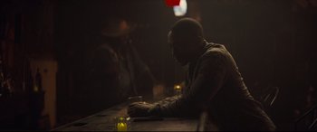 Movie still from “Synchronic” (2019), directed by Justin Benson – A man sitting at a table with a glass of wine; Medium shot, Over the shoulder angle