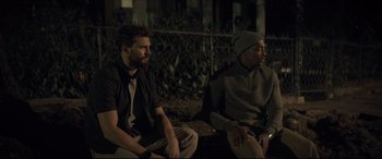 Movie still from “Synchronic” (2019), directed by Justin Benson – A couple of men sitting next to each other on top of a bench; Medium shot, Over the shoulder angle