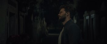 Movie still from “Synchronic” (2019), directed by Justin Benson – A man with a beard is standing in the dark; Medium shot, Over the shoulder angle