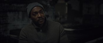 Movie still from “Synchronic” (2019), directed by Justin Benson – A man wearing a hat and a sweater looks to his left; Close Up shot, Over the shoulder angle