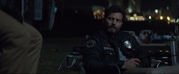 Movie still from “Synchronic” (2019), directed by Justin Benson – A man sitting on a chair in the dark; Medium shot, Over the shoulder angle