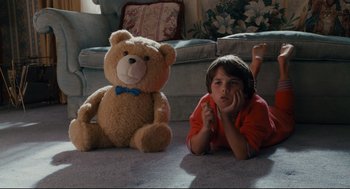 Movie still from “Ted” (2012), directed by Seth MacFarlane – A young boy laying on the ground next to a teddy bear; Wide shot, High angle