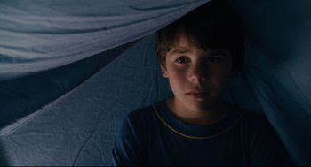Movie still from “Ted” (2012), directed by Seth MacFarlane – A young boy is under an umbrella in the dark; Close Up shot, High angle