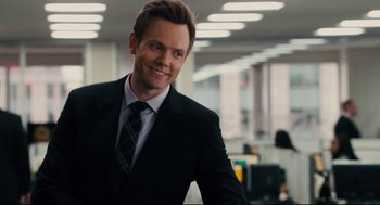 Movie still from “Ted” (2012), directed by Seth MacFarlane – A man wearing a suit and tie in an office setting; Close Up shot, Over the shoulder angle