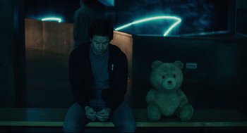 Movie still from “Ted” (2012), directed by Seth MacFarlane – A man sitting next to a teddy bear on a bench; Medium shot, Low angle