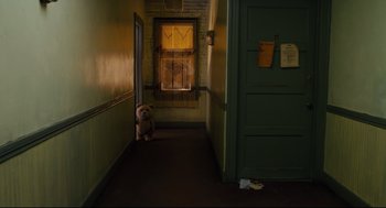 Movie still from “Ted” (2012), directed by Seth MacFarlane – A dog sitting on the floor of a hallway next to a window; Wide shot, High angle