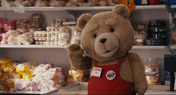 Movie still from “Ted” (2012), directed by Seth MacFarlane – A large teddy bear in a red apron is standing in front of a shelf of food; Medium shot, Over the shoulder angle