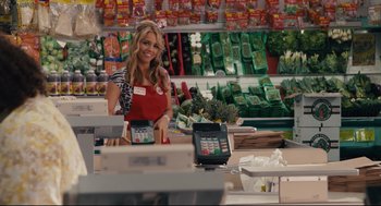 Movie still from “Ted” (2012), directed by Seth MacFarlane – A woman in a grocery store smiling for the camera; Medium shot, Over the shoulder angle