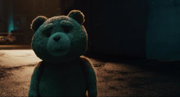 Movie still from “Ted” (2012), directed by Seth MacFarlane – A green teddy bear sitting on the ground in the dark; Close Up shot, Over the shoulder angle