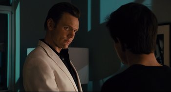 Movie still from “Ted” (2012), directed by Seth MacFarlane – A man wearing a white jacket looking at another man in a black shirt; Medium shot, Over the shoulder angle