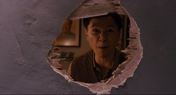 Movie still from “Ted” (2012), directed by Seth MacFarlane – A man looking through a hole in a wall; Medium shot, High angle