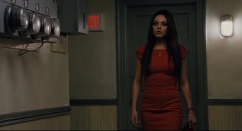 Movie still from “Ted” (2012), directed by Seth MacFarlane – A woman in a red dress standing in front of an exit sign; Medium shot, High angle