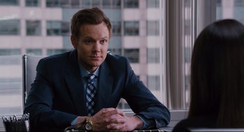 Movie still from “Ted” (2012), directed by Seth MacFarlane – A man in a blue suit sitting in front of a window; Medium shot, Over the shoulder angle
