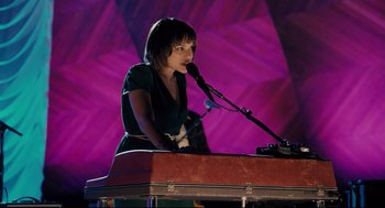 Movie still from “Ted” (2012), directed by Seth MacFarlane – A woman standing at a piano with a microphone; Medium shot, High angle