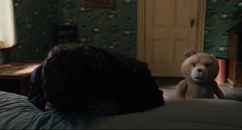 A cat laying on a bed next to a teddy bear