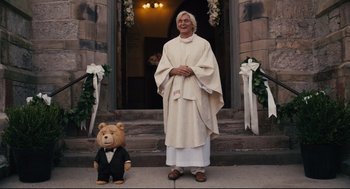 Movie still from “Ted” (2012), directed by Seth MacFarlane – A man dressed as jesus stands next to a teddy bear; Wide shot, Low angle