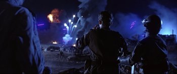 Movie still from “Terminator 2: Judgment Day” (1991), directed by James Cameron – A man is standing in front of a fireworks display; Medium shot, Over the shoulder angle