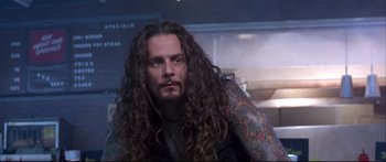 Movie still from “Terminator 2: Judgment Day” (1991), directed by James Cameron – A man with long hair and a tattoo on his arm; Close Up shot, Low angle
