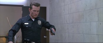 Movie still from “Terminator 2: Judgment Day” (1991), directed by James Cameron – A police officer is holding a gun in his hand; Medium shot, Low angle