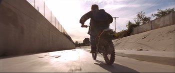 Movie still from “Terminator 2: Judgment Day” (1991), directed by James Cameron – A man riding a motorcycle down a street; Wide shot, Low angle