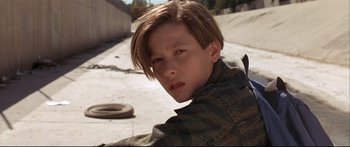 Movie still from “Terminator 2: Judgment Day” (1991), directed by James Cameron – A young boy in a plaid shirt is posing for a picture; Close Up shot, Low angle