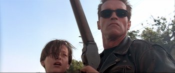 Movie still from “Terminator 2: Judgment Day” (1991), directed by James Cameron – A man and a boy holding a gun in a scene from terminator; Close Up shot, Low angle
