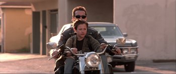 Movie still from “Terminator 2: Judgment Day” (1991), directed by James Cameron – A man on a motorcycle with a young boy; Medium shot, Low angle