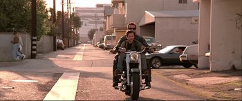 Movie still from “Terminator 2: Judgment Day” (1991), directed by James Cameron – A man and a woman riding a motorcycle down a street; Wide shot, Low angle