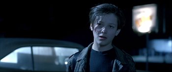 Movie still from “Terminator 2: Judgment Day” (1991), directed by James Cameron – A young man standing in front of a car at night; Close Up shot, High angle