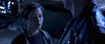 Movie still from “Terminator 2: Judgment Day” (1991), directed by James Cameron – A young person is talking to another person in a dark room; Close Up shot, Over the shoulder angle
