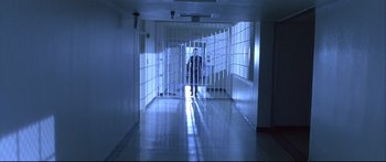 Movie still from “Terminator 2: Judgment Day” (1991), directed by James Cameron – A man standing in a jail cell in a dark room; Wide shot, High angle